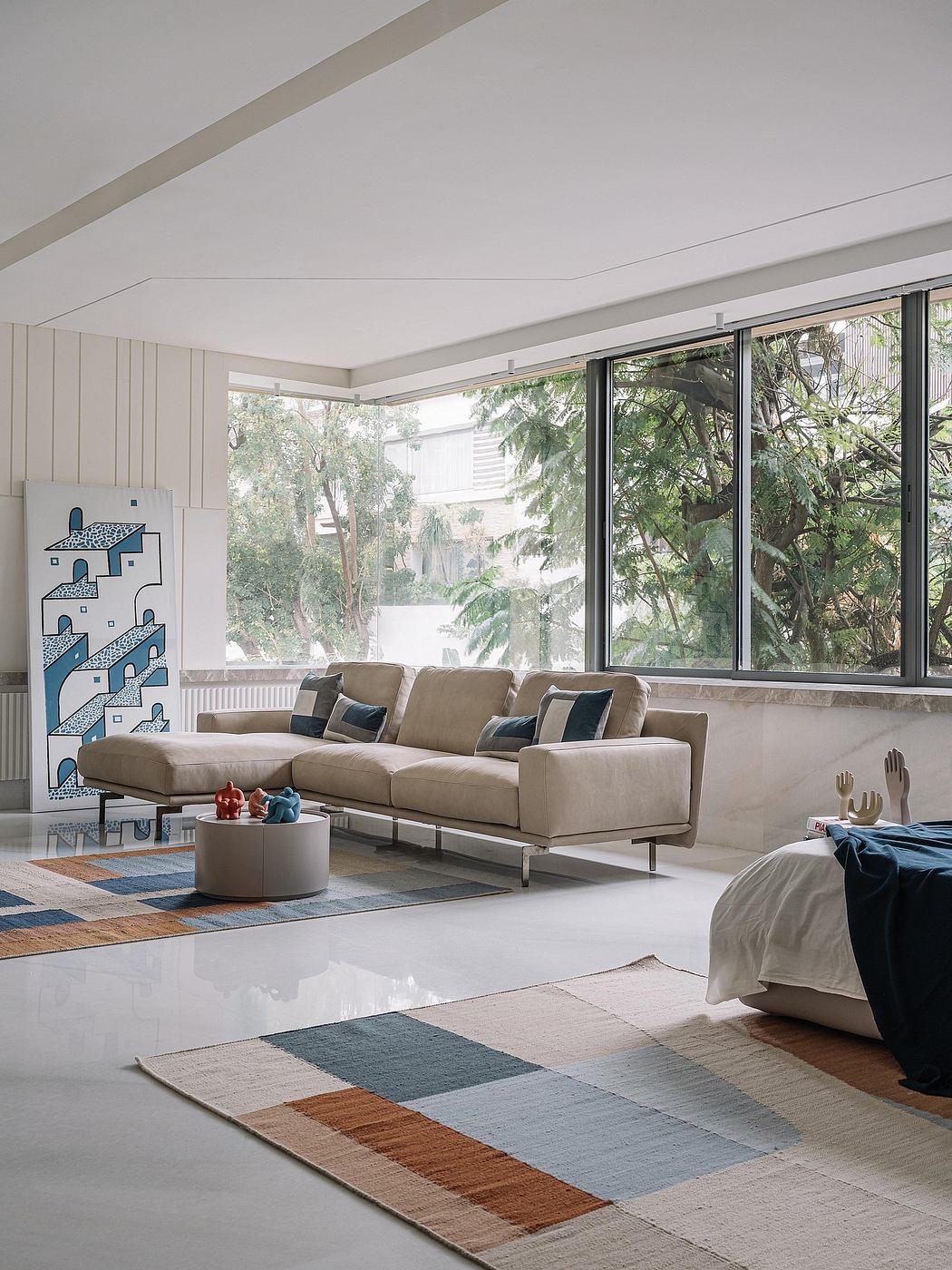 Spacious modern living room with large windows, plush sofa, and abstract artwork.