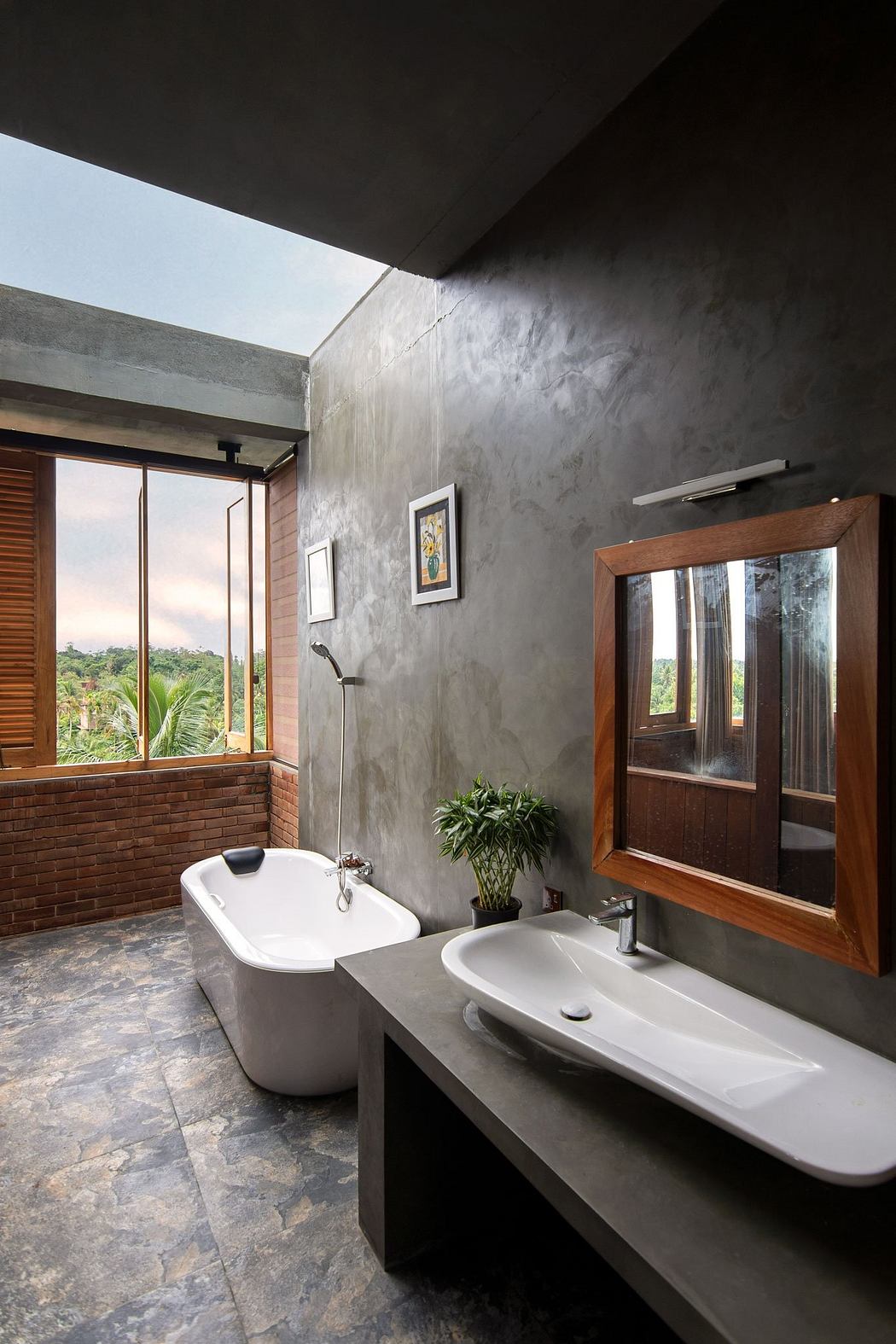 A modern bathroom with a freestanding tub, double vanity, and large windows overlooking greenery.