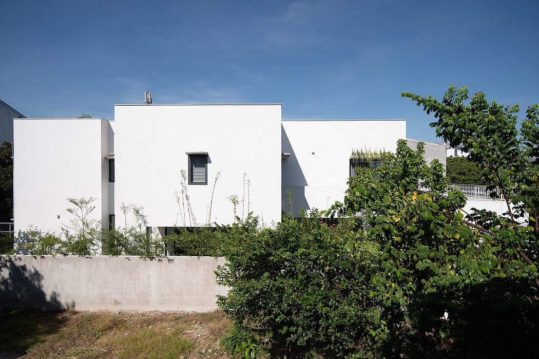 Contemporary white building with greenery against a blue sky.