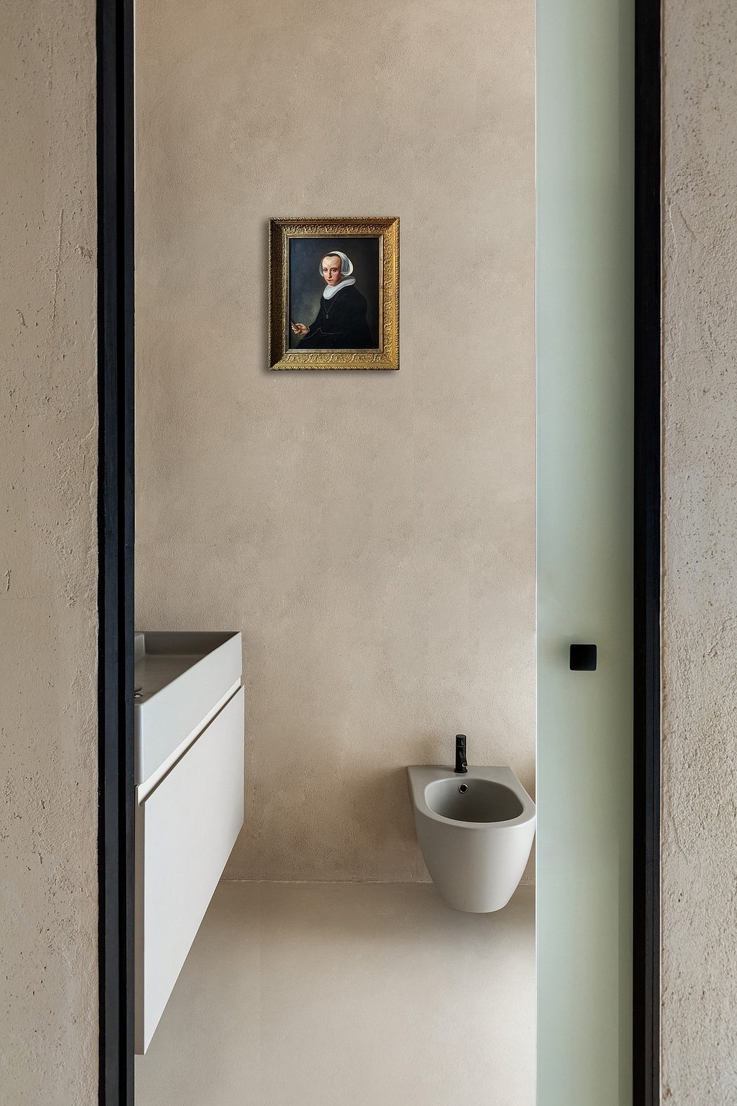 A minimalist bathroom with a portrait in a gilded frame on the beige wall.