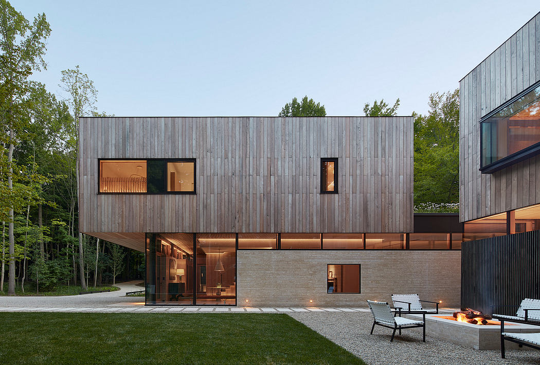 Modernist home with layered wood siding, floor-to-ceiling windows, and outdoor lounge area.