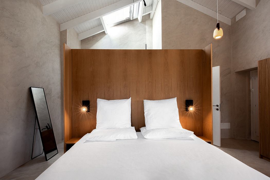 Minimal modern bedroom with wooden headboard, recessed lighting, and concrete walls.