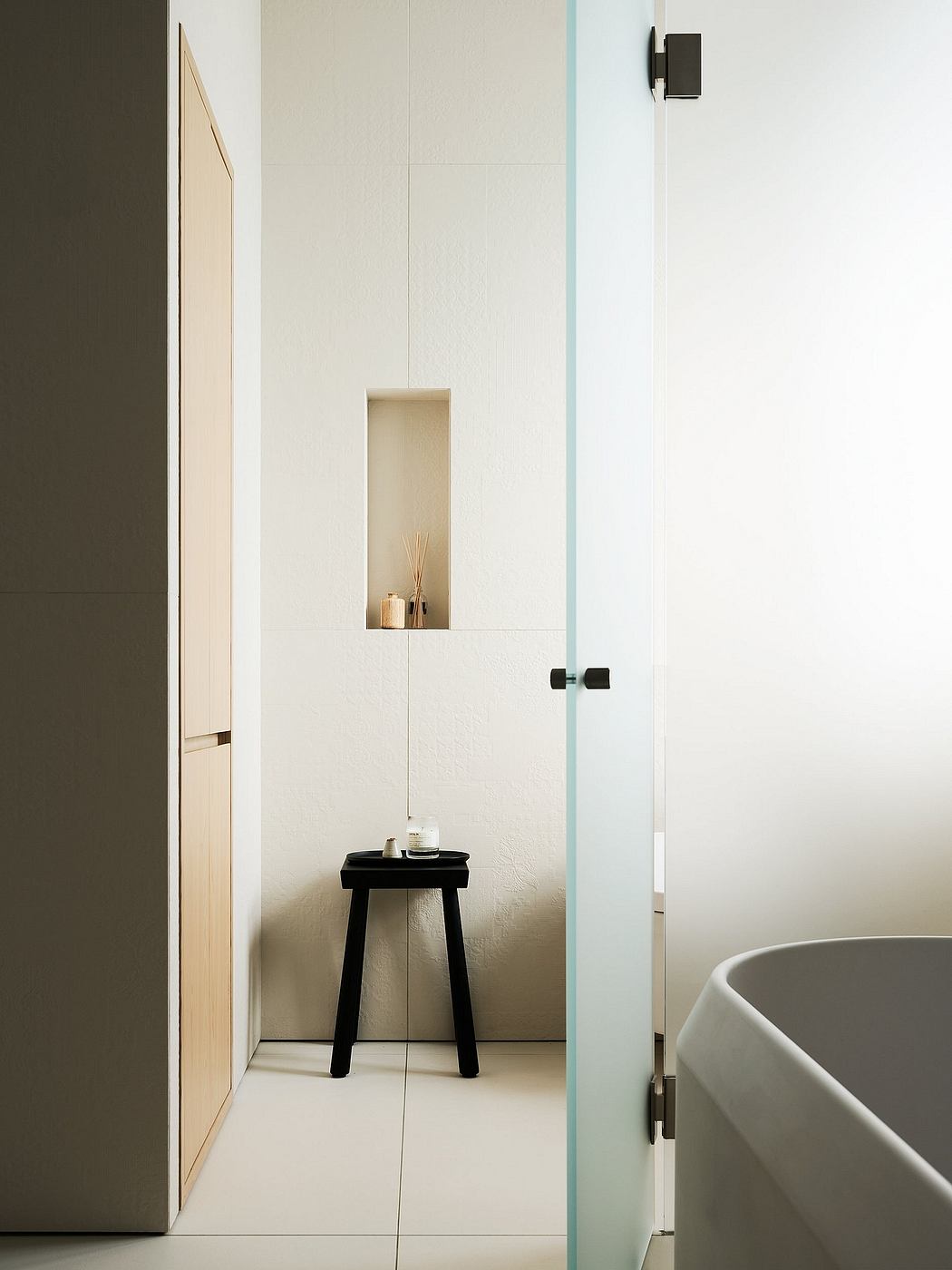 Minimalist bathroom interior with sleek glass partition, wooden vanity, and recessed niche.
