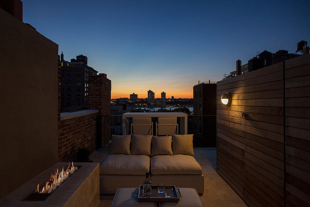 Cozy outdoor seating arrangement with city skyline view at sunset. Modern architectural details.