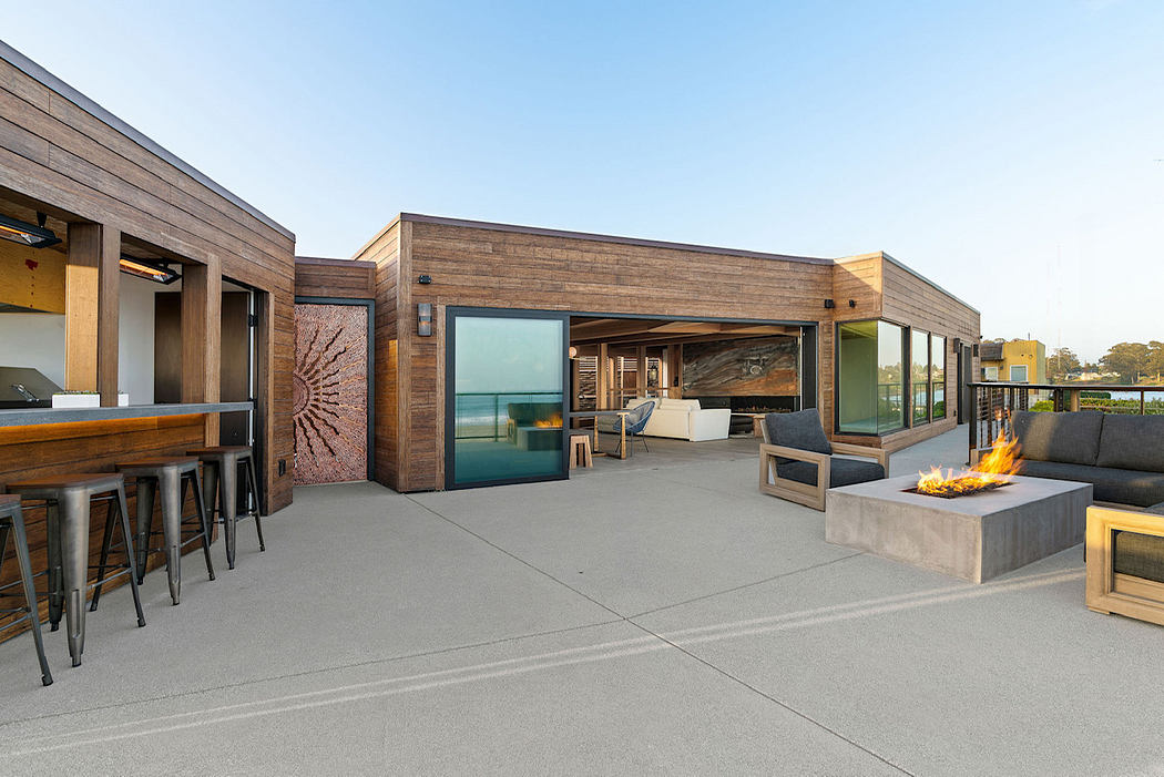 A modern architectural exterior with a covered outdoor seating area, bar, and fireplace.