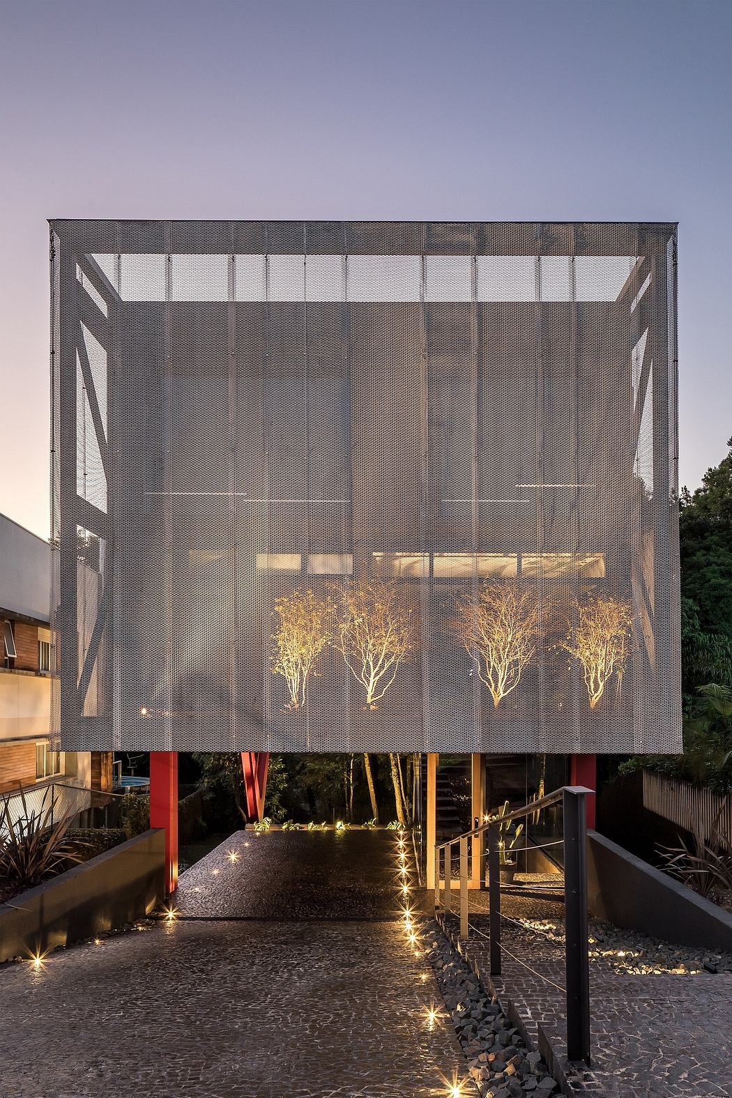 Modern architectural structure with geometric grid facade and illuminated trees.