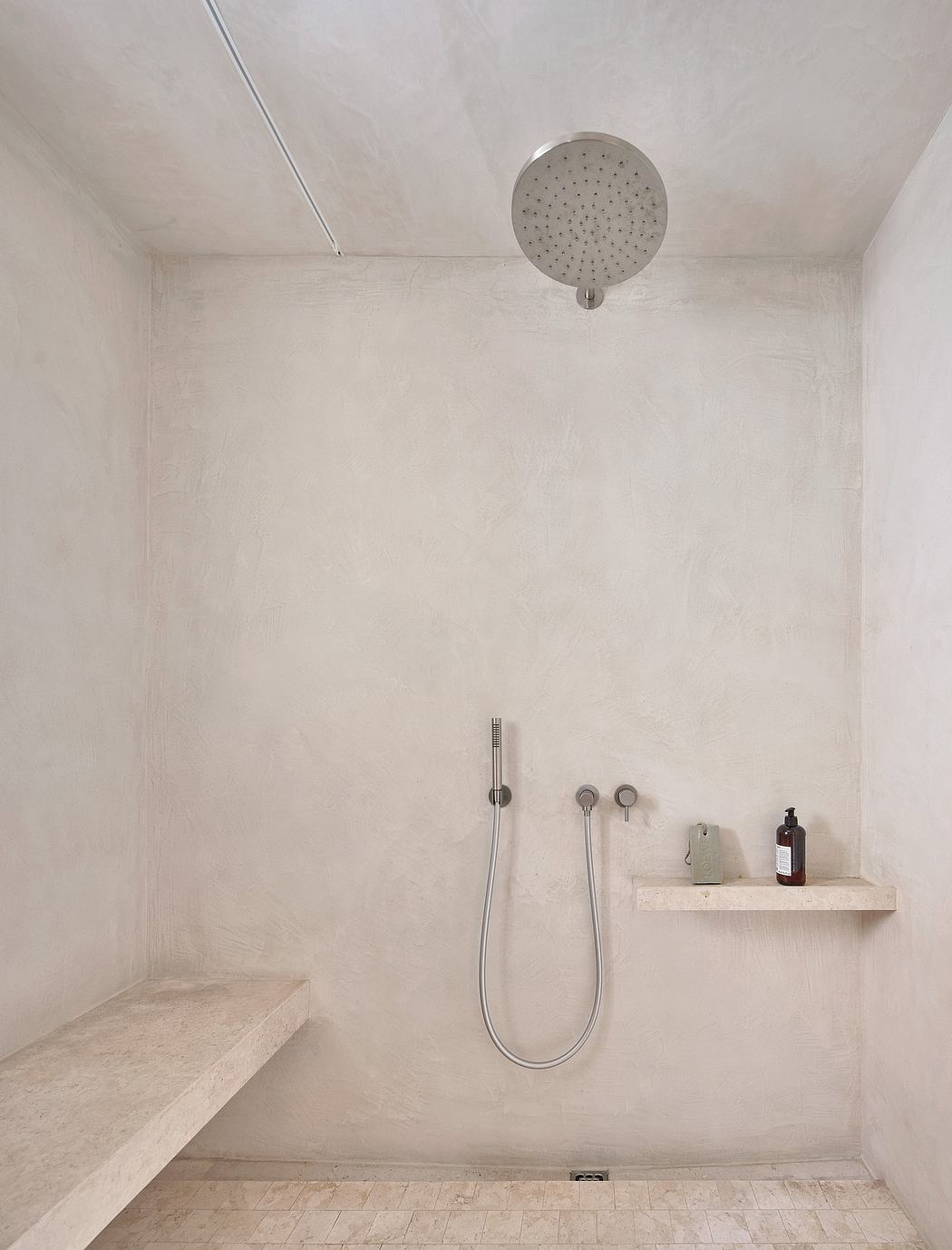 Minimalist bathroom design with a large ceiling-mounted showerhead and simple shelving.