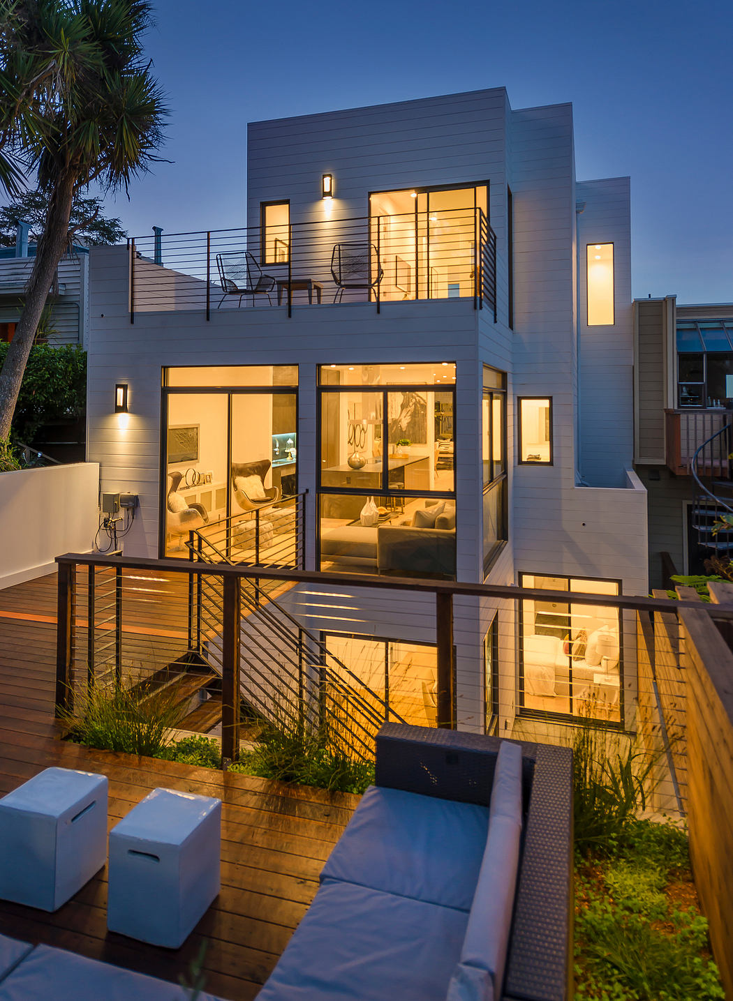 Contemporary two-story home with modern architecture, spacious balcony, and warm interior lighting.