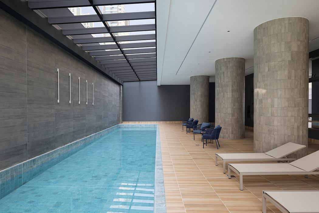 Sleek, modern indoor pool area with gray tiled walls, wood-paneled floors, and lounge chairs.