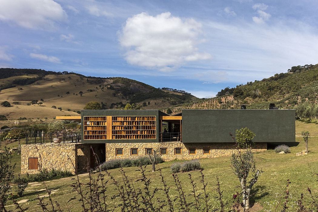 A modern countryside house with a stone base and timber-framed upper floors, set against rolling hills.