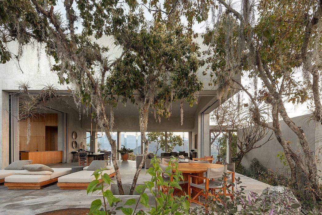 Expansive glass-walled home nestled among lush greenery and mature trees, showcasing an inviting indoor-outdoor living space.