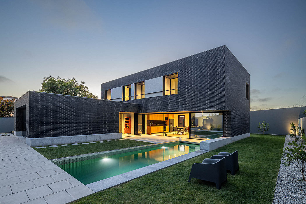Modern two-story home with sleek black brick exterior, large windows, and a pool.