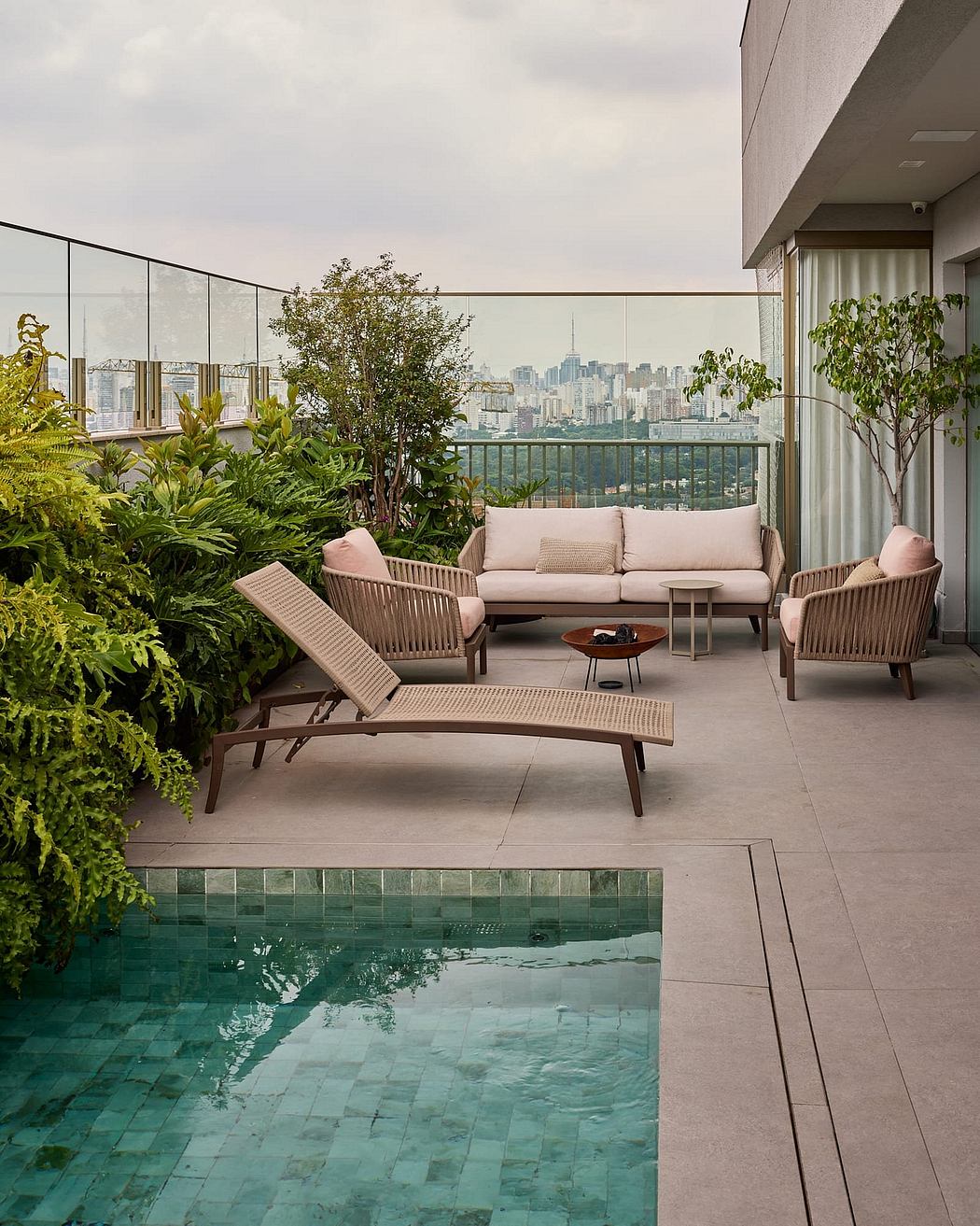 Lush, modern balcony retreat with city skyline, pool, and plush rattan furnishings.
