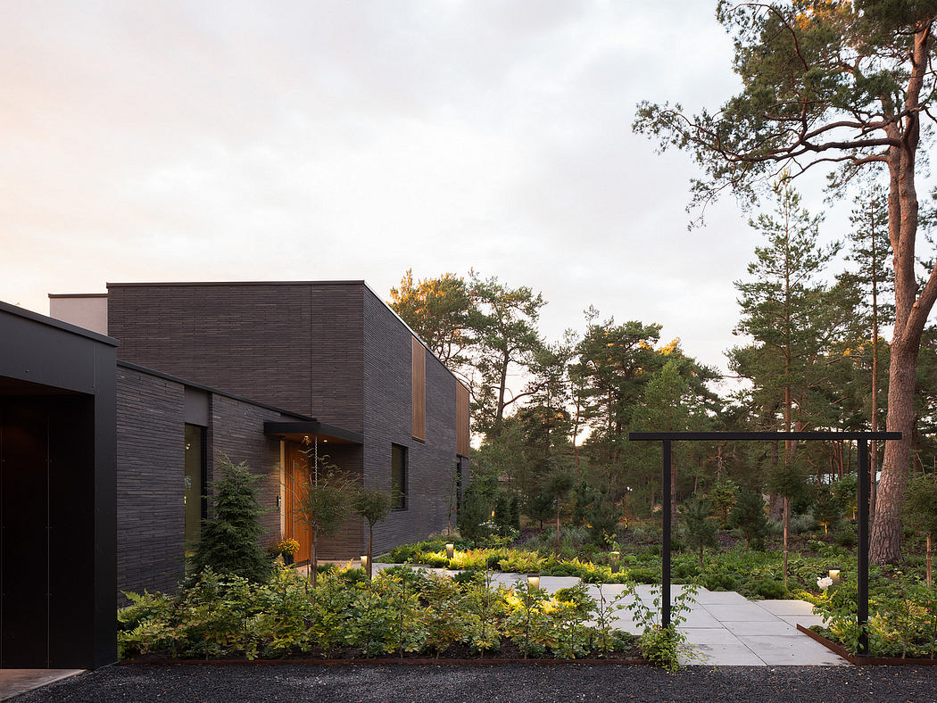 Modern, wood-clad exterior with landscaped garden and paths in a forested setting.