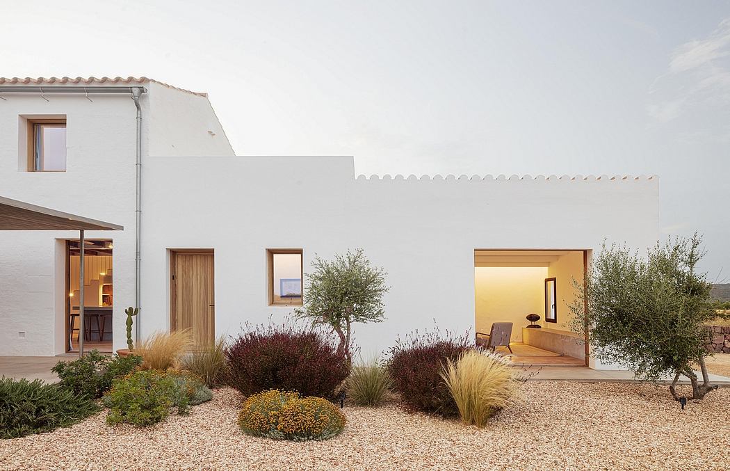 A modern white villa with wooden details, surrounded by a well-designed Xeriscape landscape.