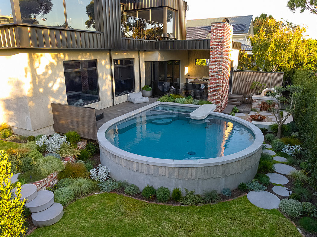 Stunning backyard oasis with a circular in-ground pool, lush landscaping, and contemporary architecture.