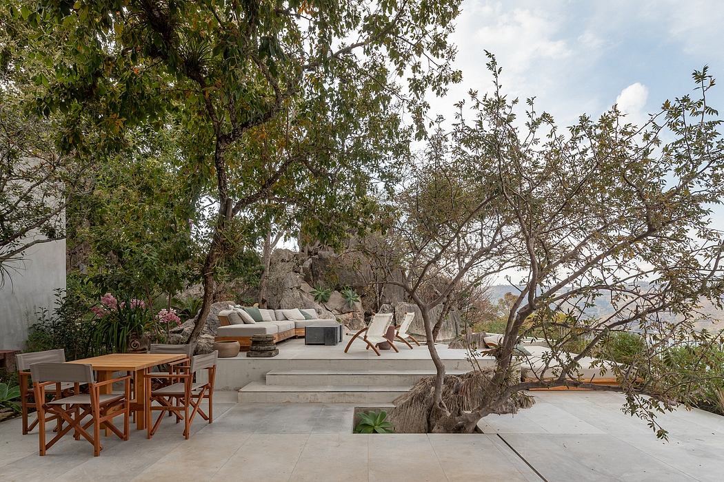 Lush outdoor lounge area with concrete patio, wood furniture, and surrounding greenery.