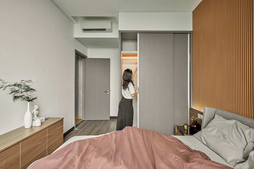A modern bedroom with minimalist decor, wooden accents, and sliding closet doors.
