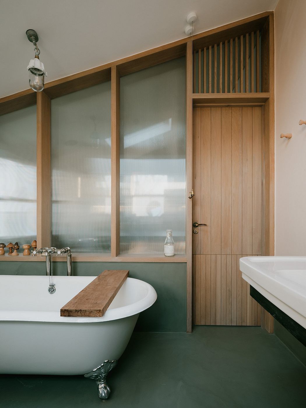 A modern bathroom with a clawfoot tub, wooden paneling, and a glass partition.