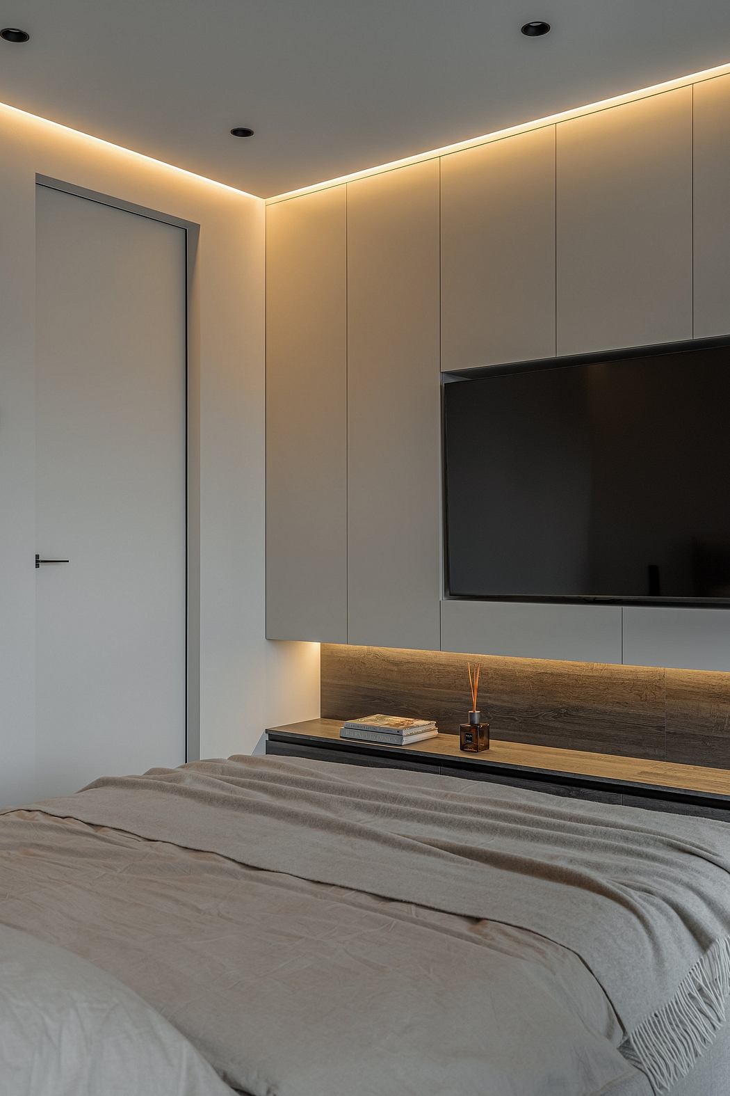 Minimalist bedroom design with recessed lighting, wood accents, and built-in TV cabinet.