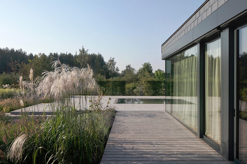 Sleek modern architecture with a wooden deck overlooking a lush garden and pond.