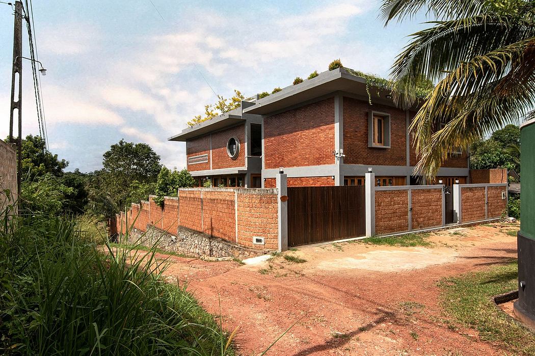 A modern brick house with a slanted roof, surrounded by lush vegetation.