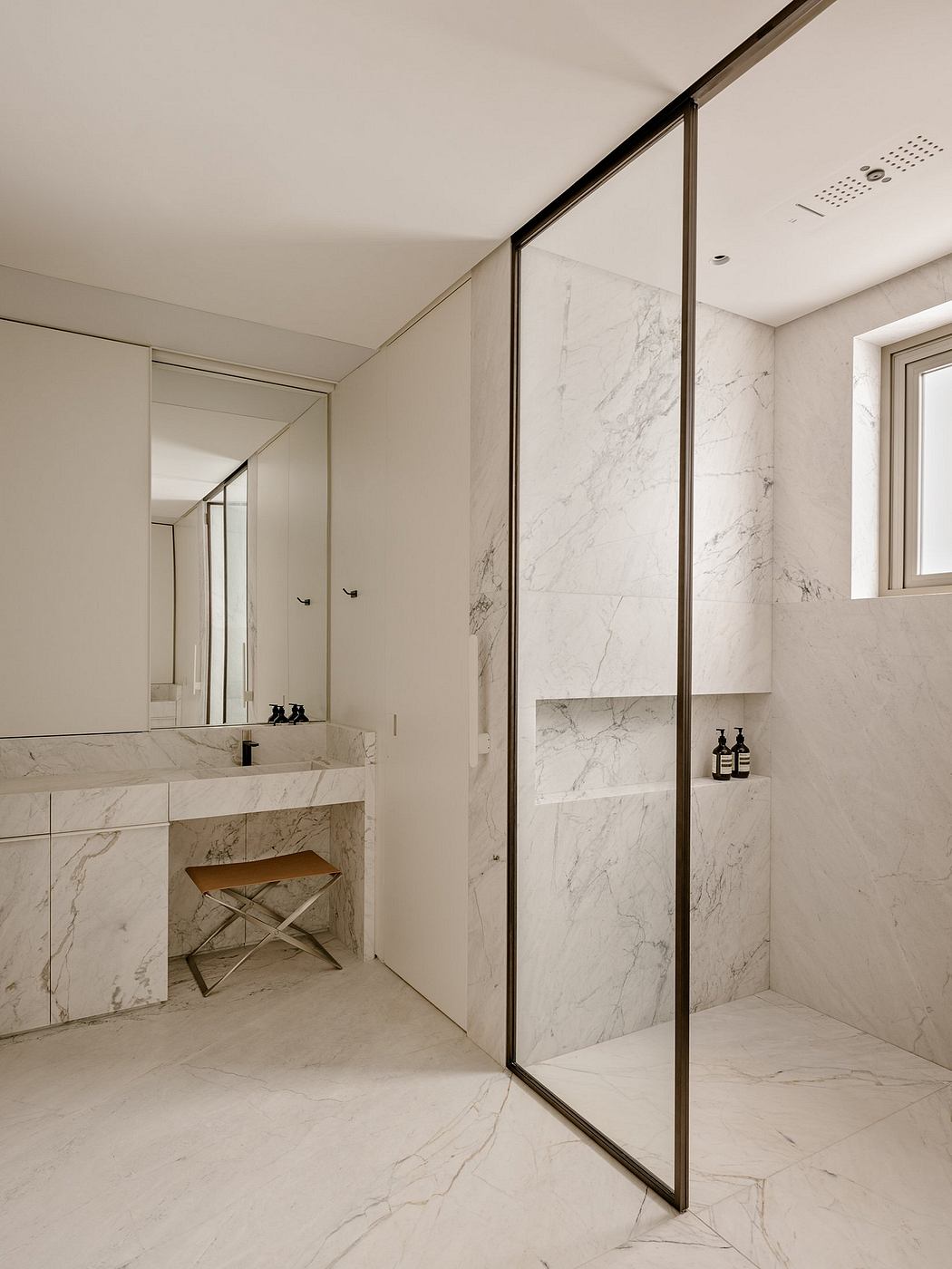 Sleek, minimalist bathroom with marble walls, modern fixtures, and a wooden bench.