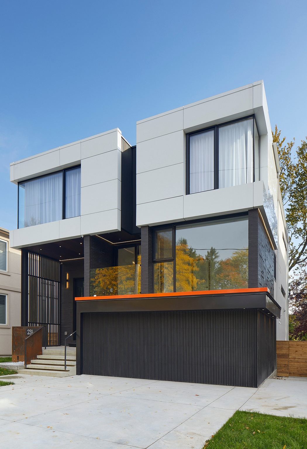 Modern, minimalist-styled residential building with clean lines, large windows, and a recessed garage door.
