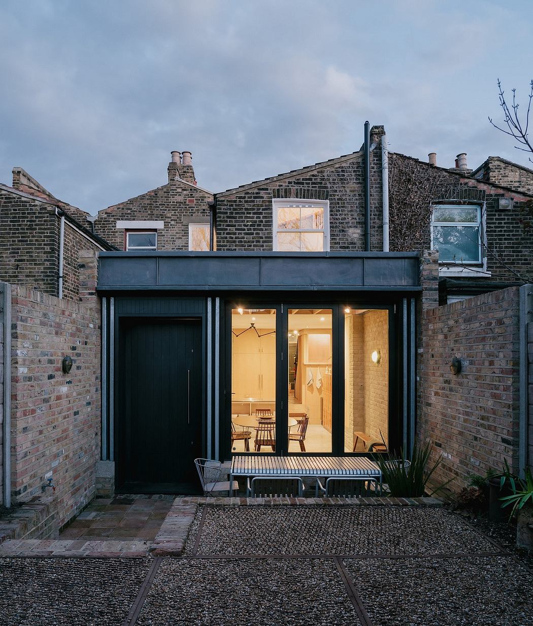 Exterior of a modern brick home with sleek black windows and an open patio area.