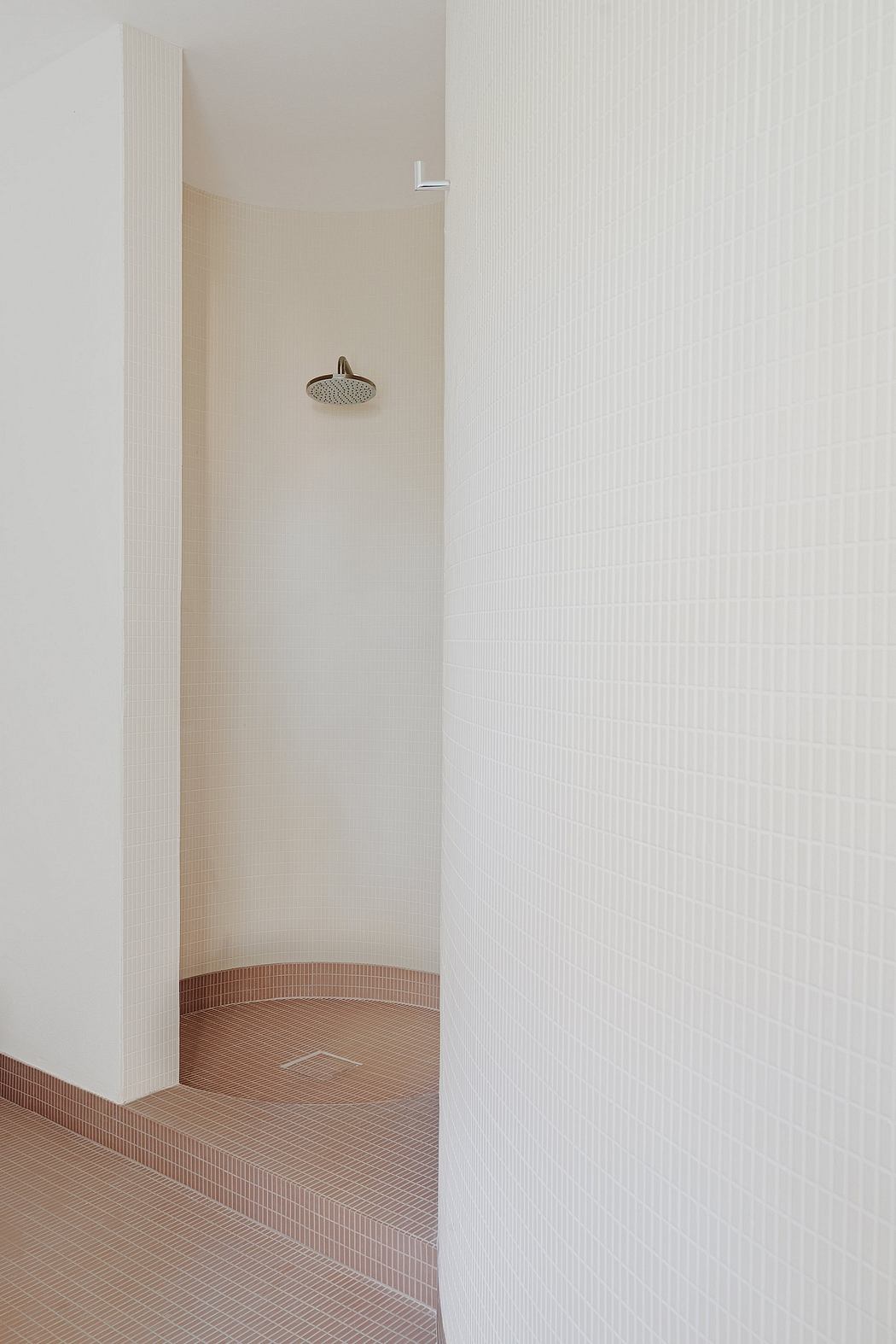 Minimalistic bathroom design showcases sleek, modern shower fixture and textured tiles.