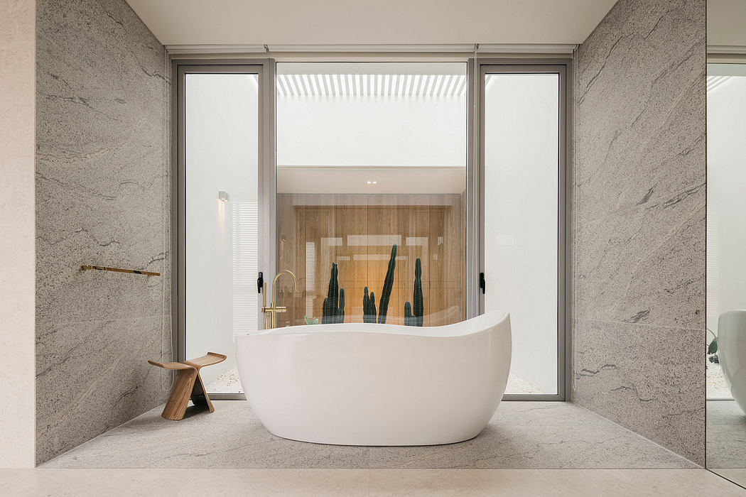 Minimalist bathroom with freestanding bathtub, wooden wall panels, and large windows.