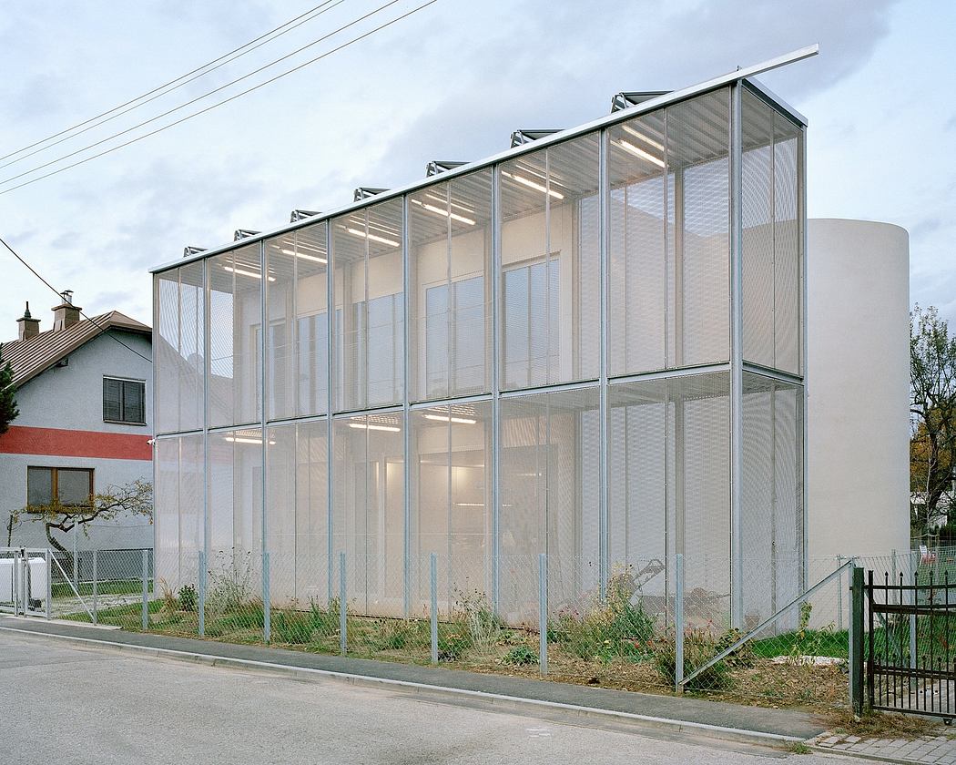 Modernist glass and metal structure with angled roof and suspended lighting.