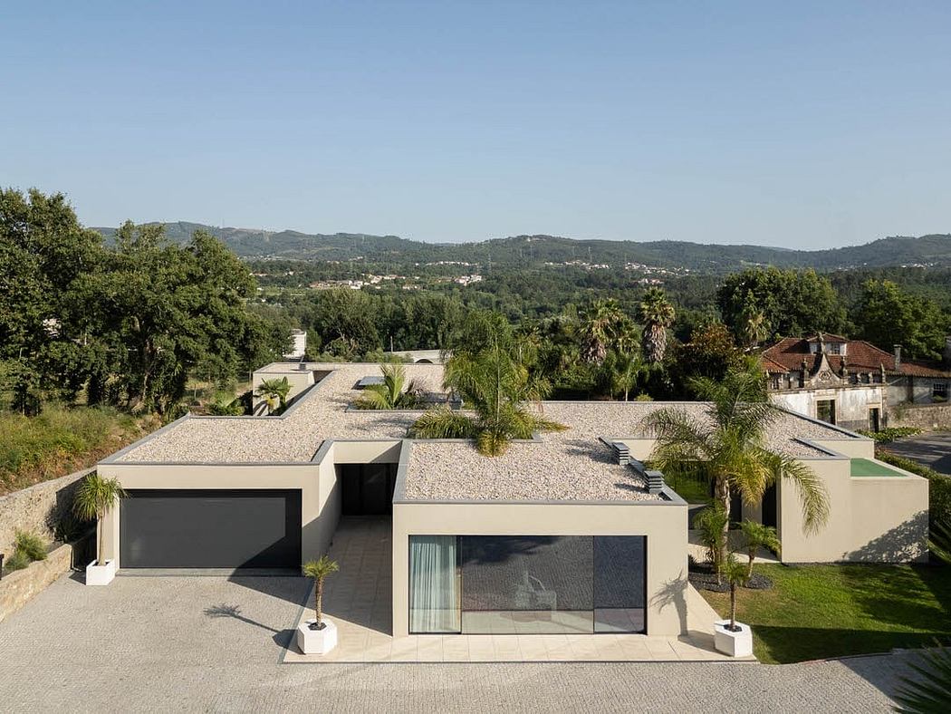 Modern home with clean lines, flat roof, and large glass panels overlooking lush, hilly landscape.