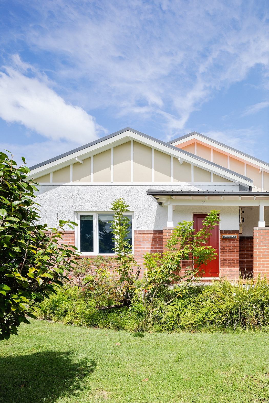 Well-maintained suburban residence with brick exterior, peaked roof, and lush landscaping.