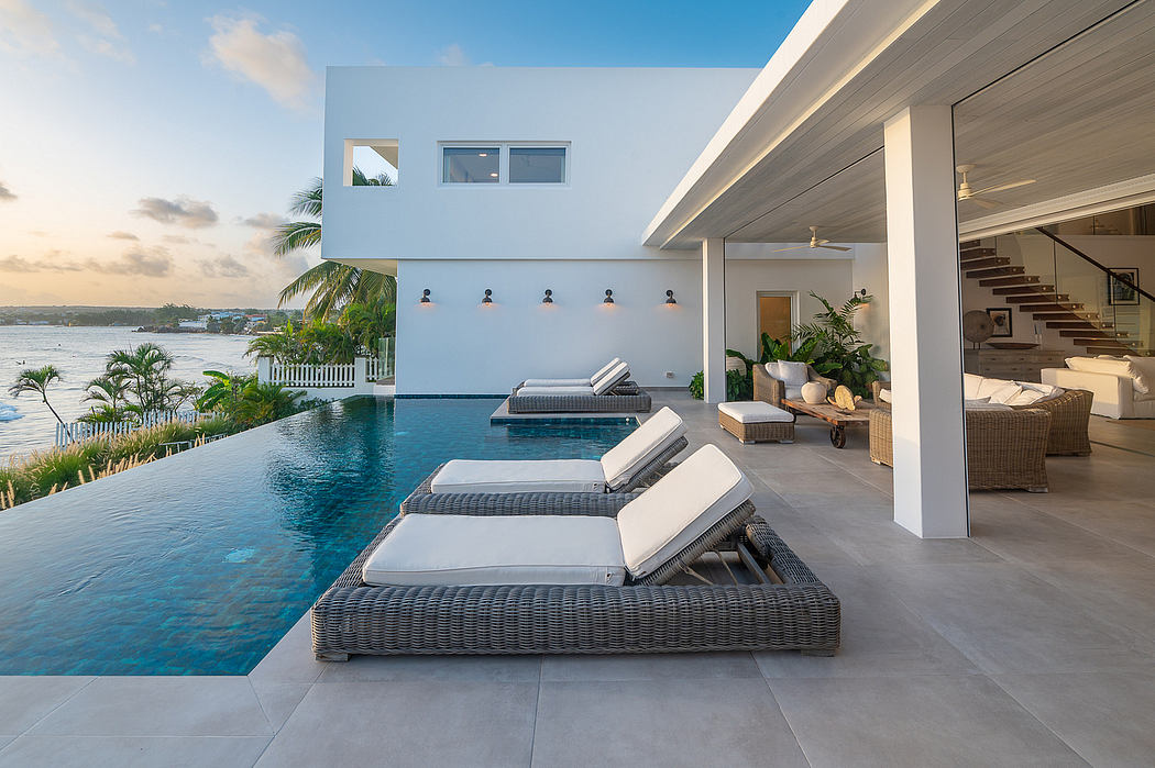 Sleek modern villa with infinity pool, patio seating, and lush tropical surroundings.