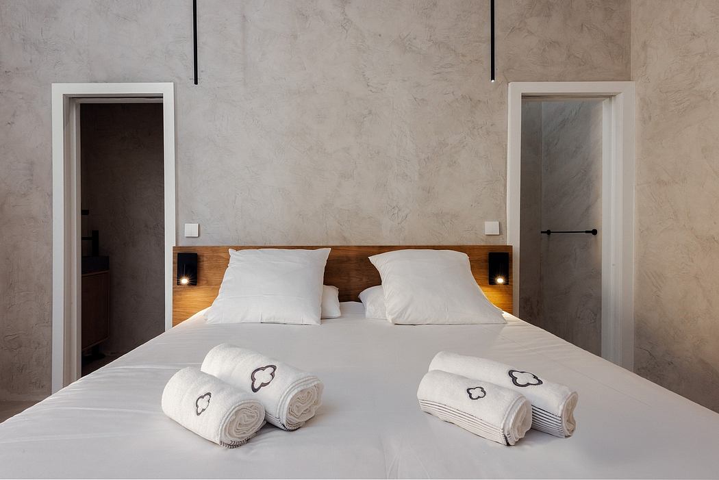 Minimalist bedroom with wooden headboard, white linens, and textured concrete walls.