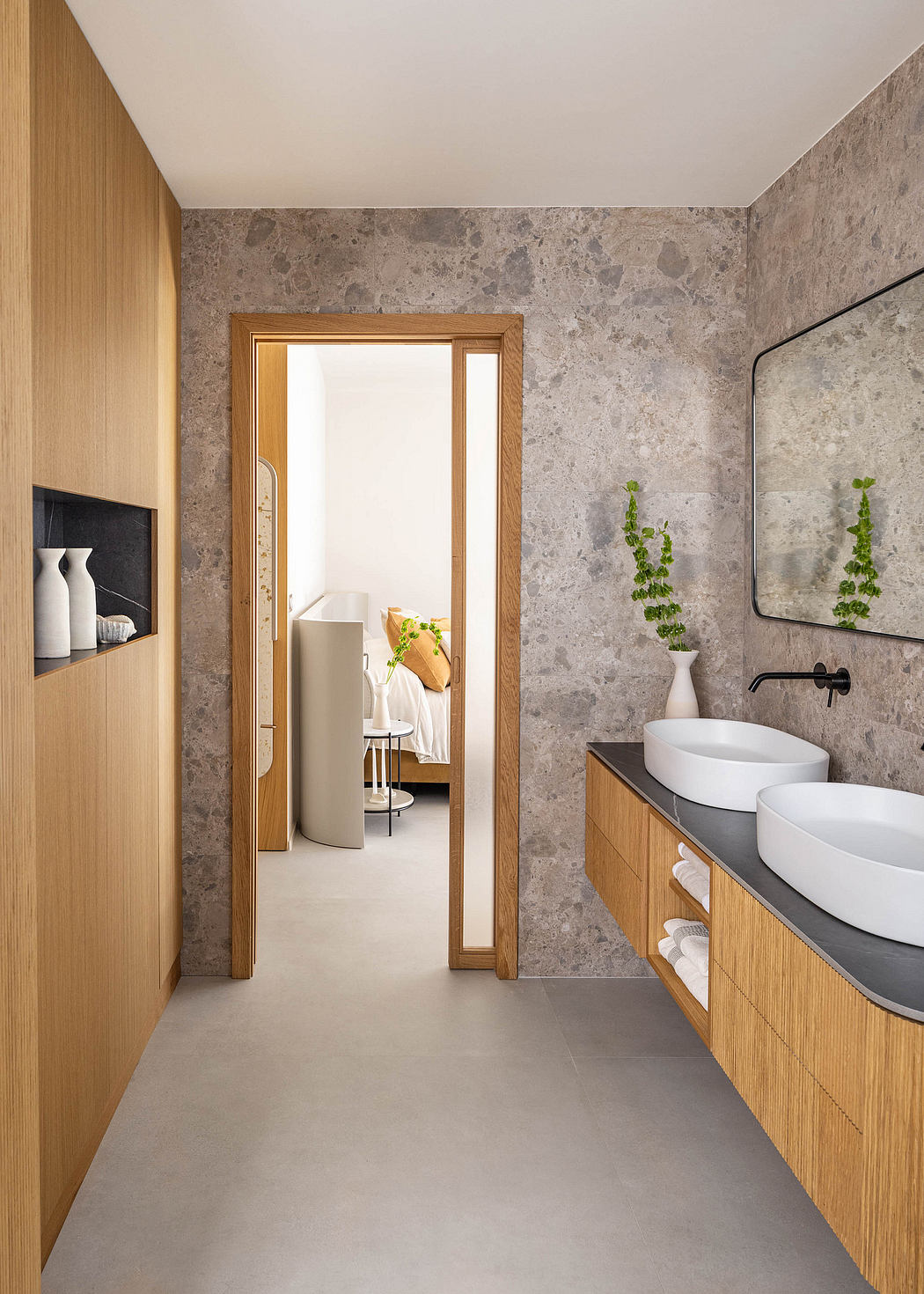 Minimalist bathroom with wooden vanity, white vessel sinks, and textured gray walls.