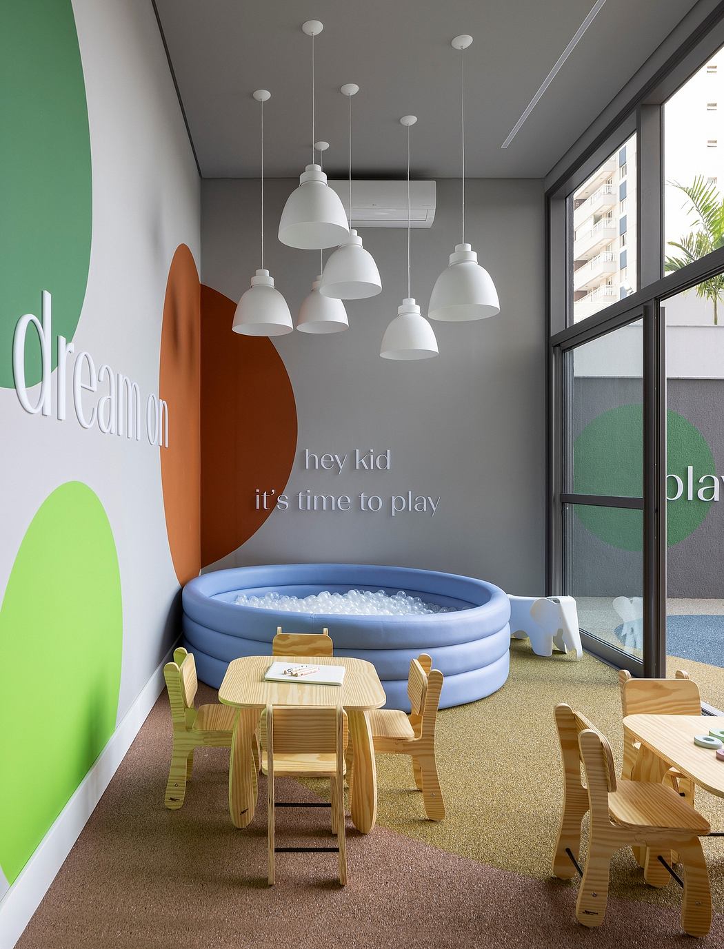 Bright, playful room with colorful walls, suspended lights, and kid-friendly furniture.