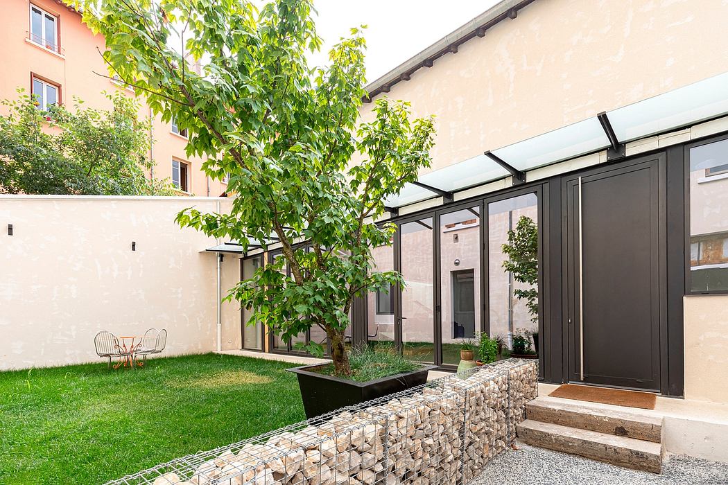 Cozy courtyard with well-designed modern architecture, featuring a tree and landscaping elements.
