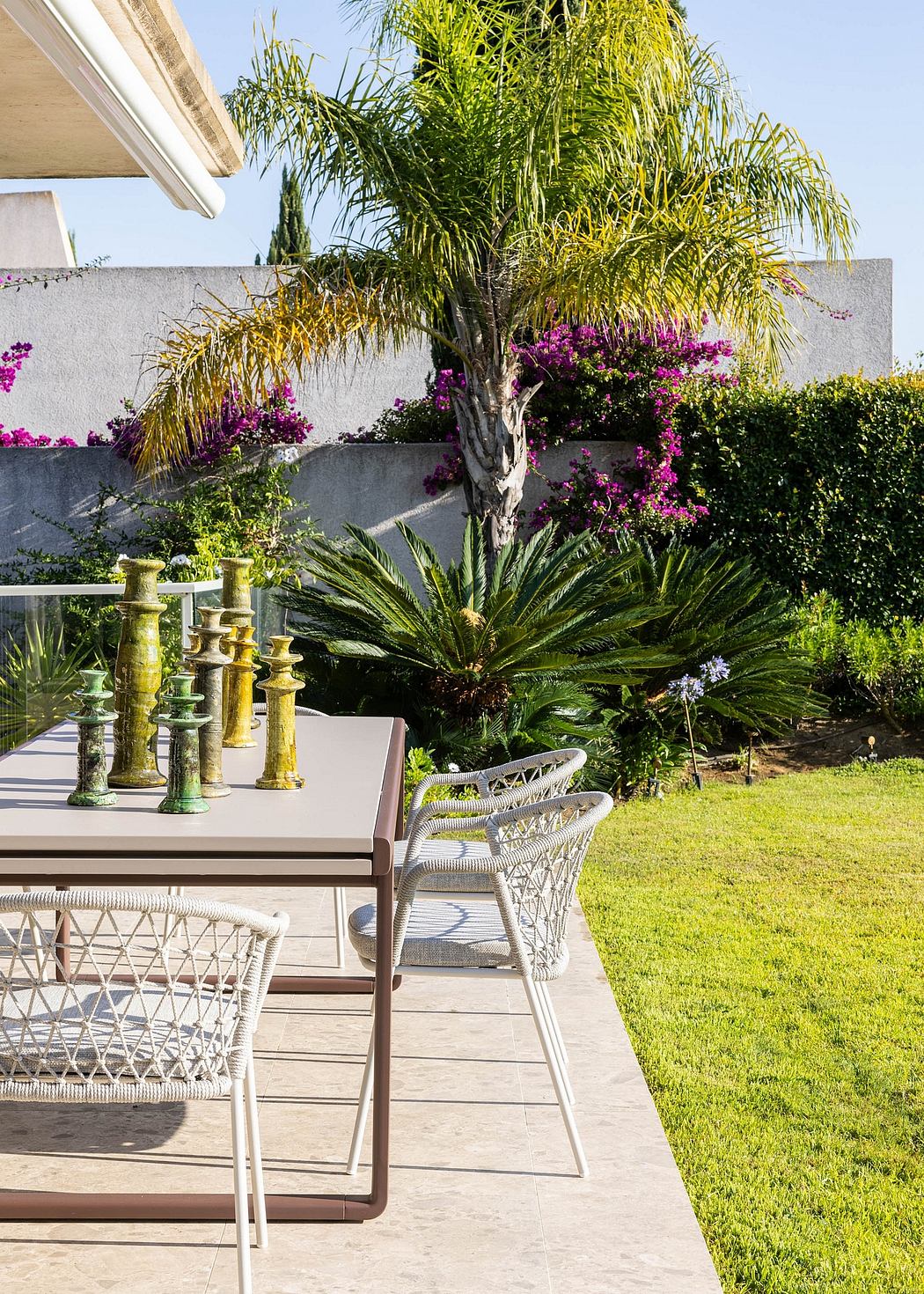 Lush tropical garden with patio furniture, vibrant flowers, and decorative candlesticks.
