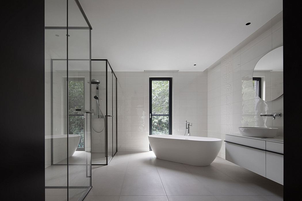 Sleek, modern bathroom with freestanding tub, glass shower, and large window overlooking nature.