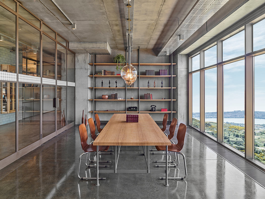 Spacious modern meeting room with concrete ceiling, metal shelving, and panoramic view.