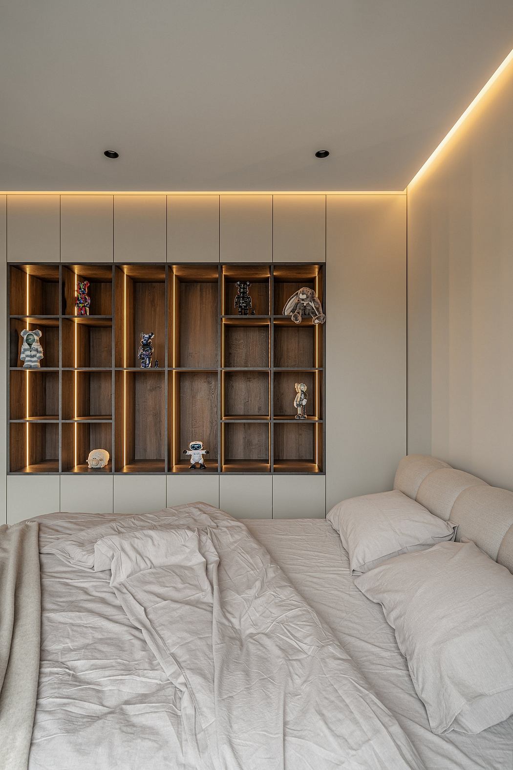 Cozy bedroom with warm-toned built-in shelving, soft lighting, and piles of bedding.