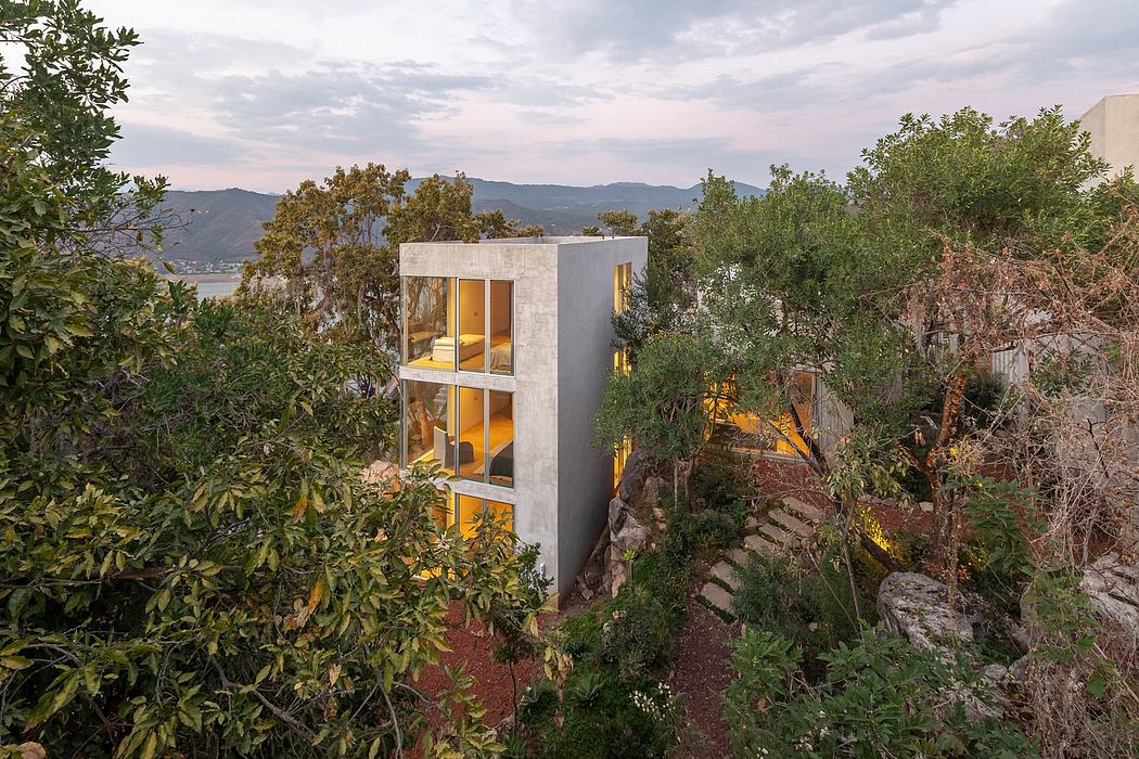 A modern, multi-level concrete structure nestled among lush greenery and rocky terrain.