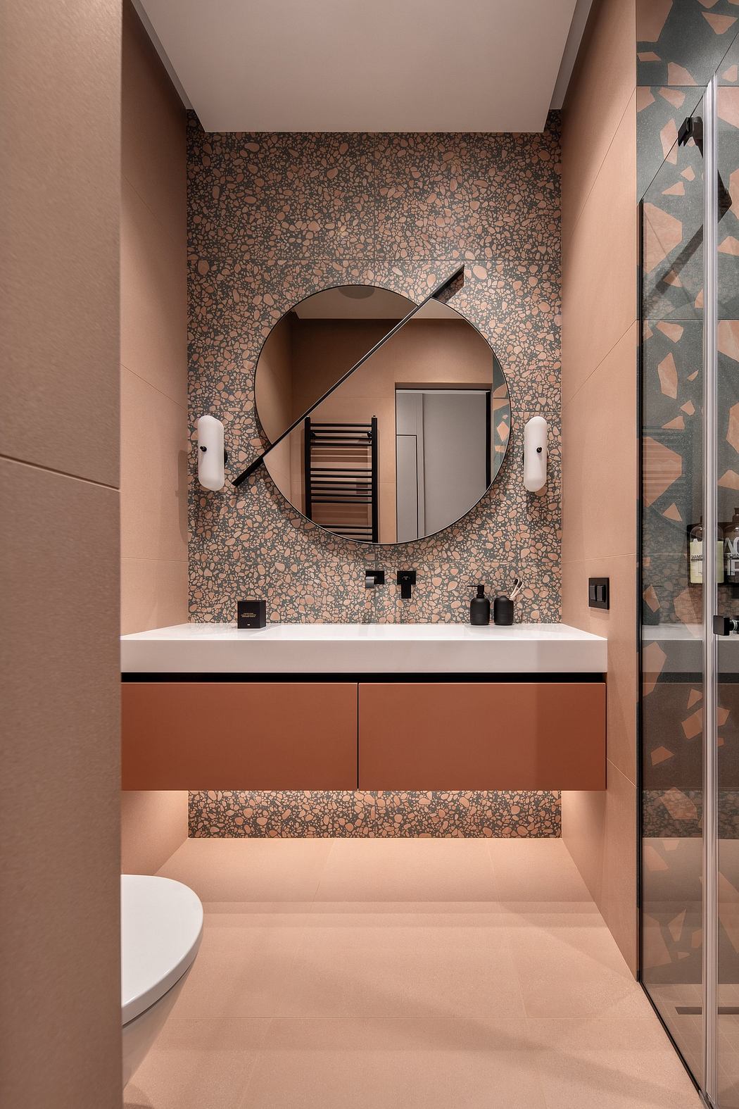 A contemporary bathroom with a round mirrored vanity, geometric wall tiles, and minimalist fixtures.