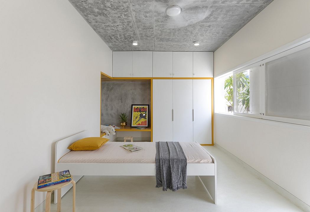 A modern bedroom with a concrete ceiling, white walls, and minimal furnishings creating a serene ambiance.
