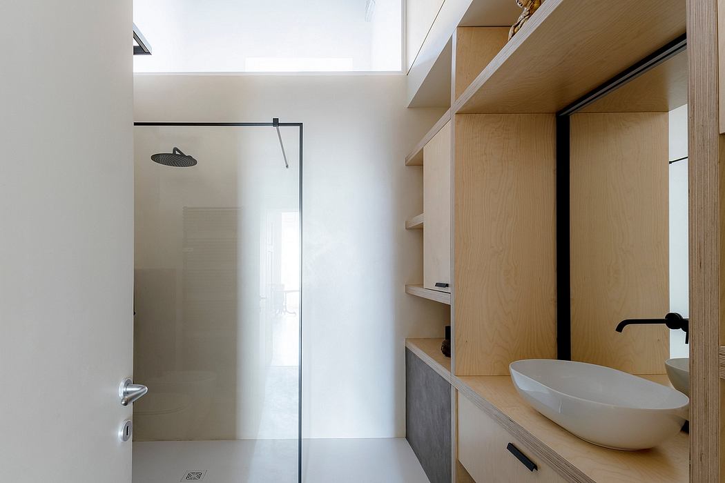 A minimalist bathroom with a modern shower, wooden cabinetry, and a vessel sink.