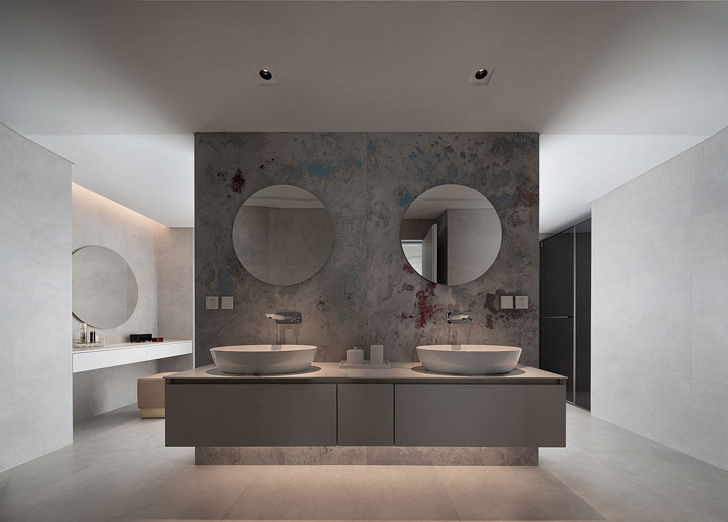 A modern, minimalist bathroom with a marble-clad wall, double vanity, and round mirrors.