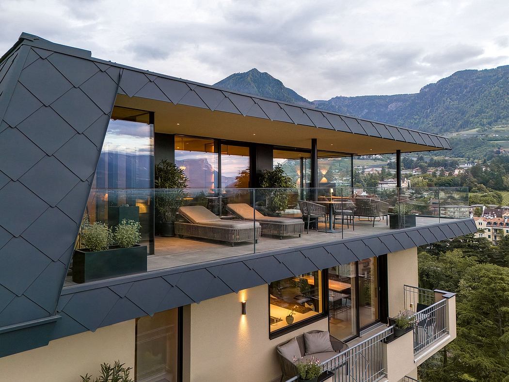 Contemporary mountain lodge with expansive glass walls, angled roof, and furnished deck.
