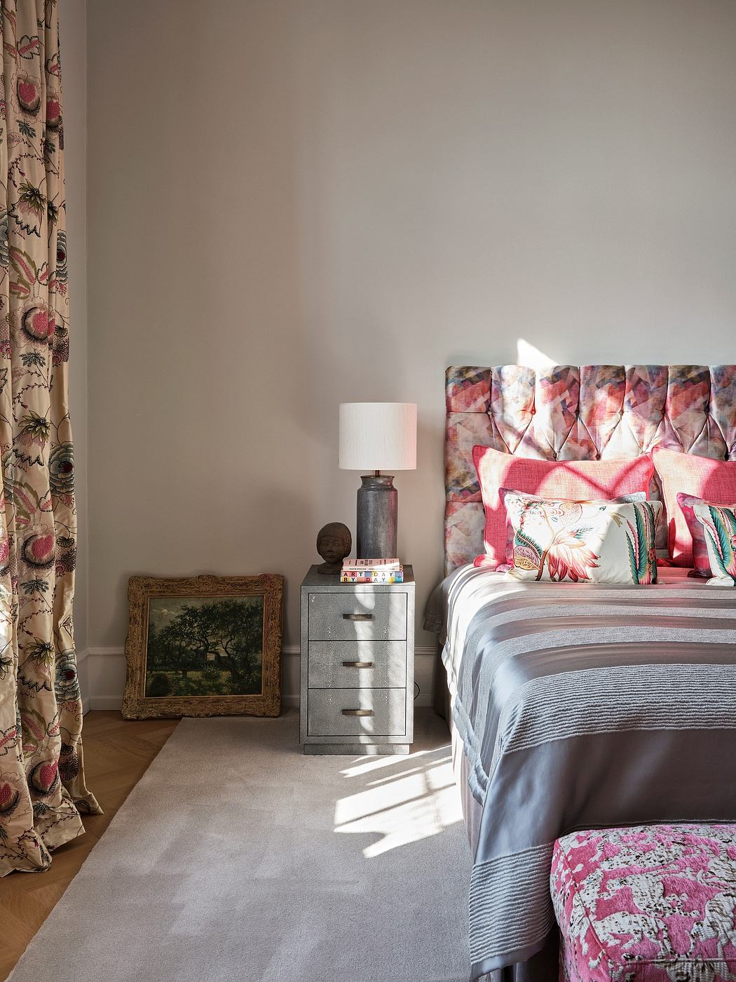 Cozy bedroom with floral curtains, patterned bedding, and a metallic dresser.